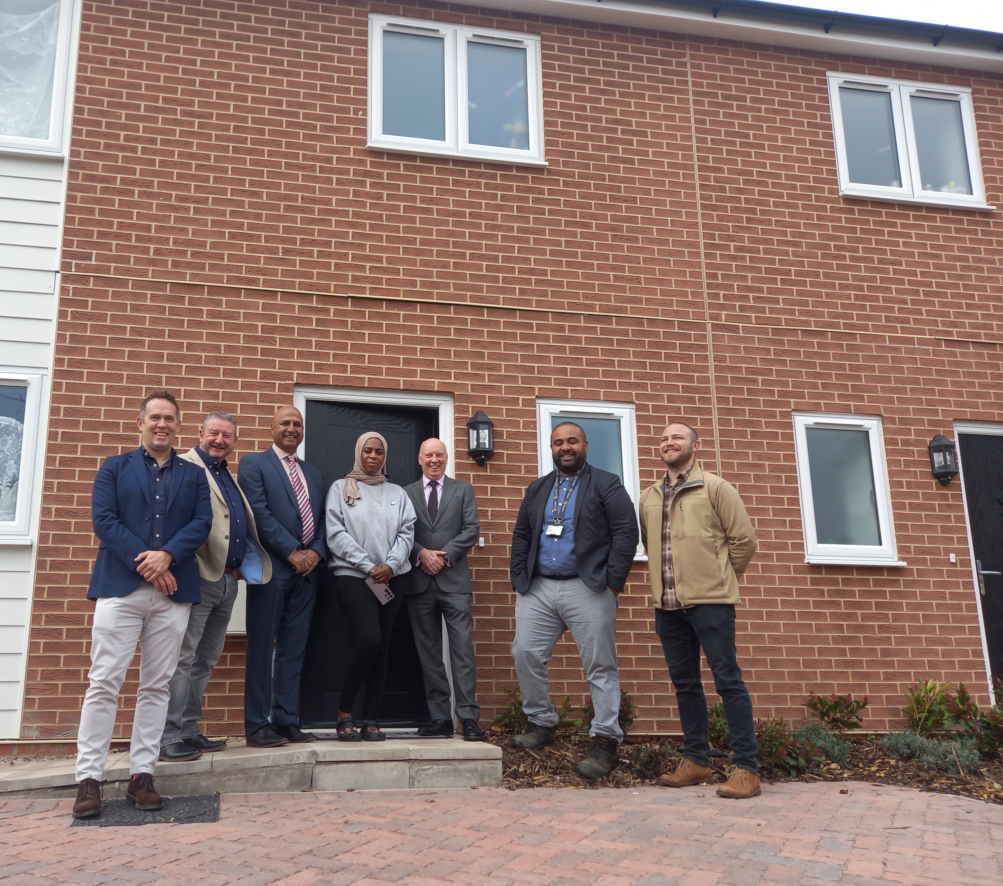 Councillor Naeem Akhtar and with partners and resident outside new house build on old Garage site Bell Green