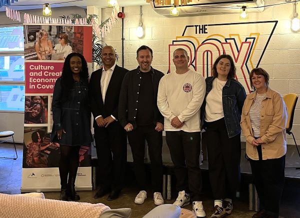 Music mixer panellists stood infront of a sign for 'The Box' venue